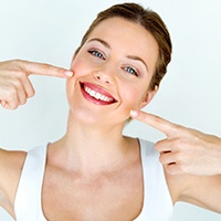 Woman pointing to her beautiful teeth.