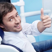 man in dental chair giving thumbs up