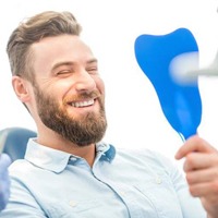 Man smiling in mirror at dental office