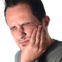 Man holding cheek in pain