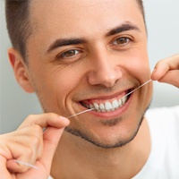 A young man flossing his teeth