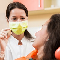 dentist in Manchester holding up an extracted tooth for a patient to see